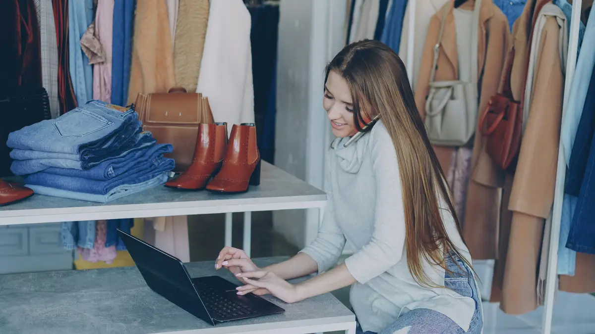 Dueña de una tienda trabajando en su laptop junto al mostrador.