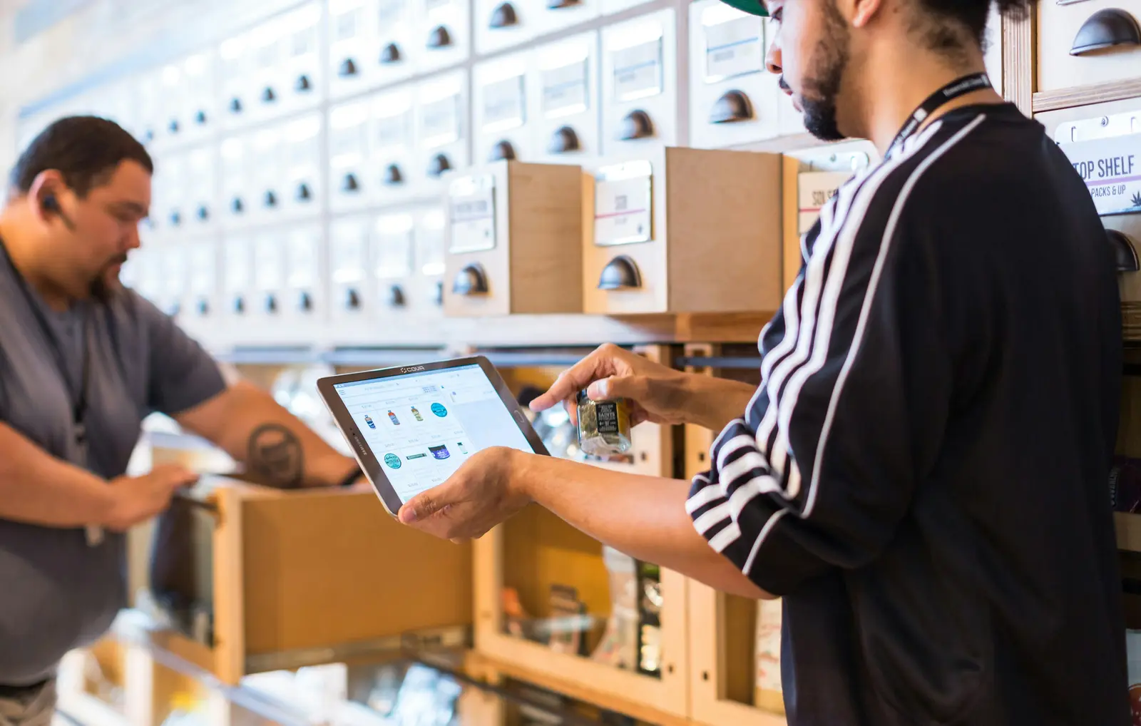 Dueño de una tienda mostrando un inventario en una tablet a un empleado.